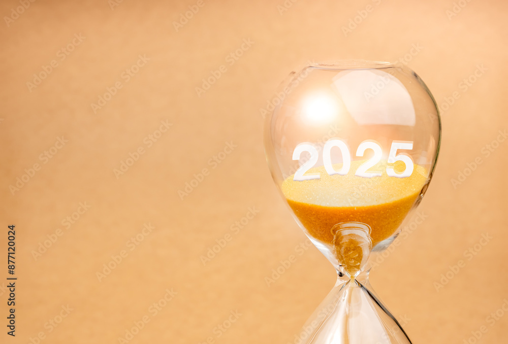 Wall mural Coming soon to happy new year 2025, business concept. Close-up 3d 2025 year calendar number drown on gold sand inside hourglass isolated on eco light brown background with copy space, minimal style.