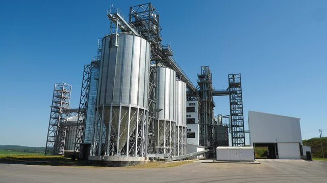 large modern grain elevator in field on sunny summer day, metal tanks for grain