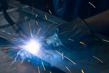 Detail of heavy industry manufacturing, sparks come out of a metal working welder.