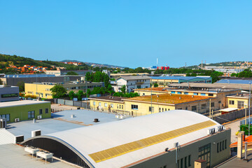 Building with a large white roof in the city. The roof is slanted and has a curved shape. The building is surrounded by other buildings © Leilani