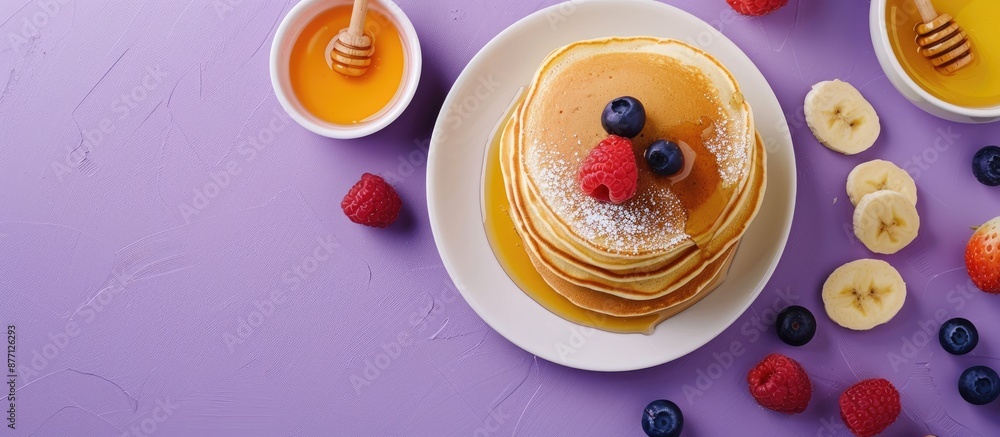 Aufkleber Top-down view of pancakes with honey and sweets presented on a purple backdrop with a blank area ideal for adding text or graphics - copy space image.