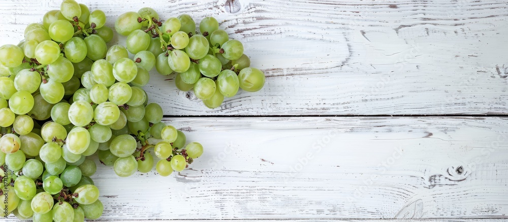 Poster fresh white grapes on a white wooden surface with a top view, providing ample copy space image.