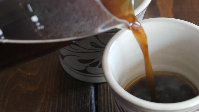 淹れたての熱いコーヒーをマグカップに注ぐクローズアップ動画。左から右へ。