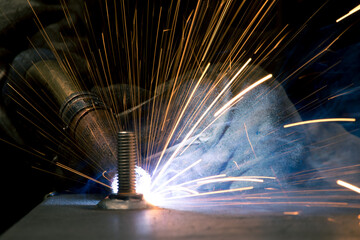 Detail of heavy industry manufacturing, sparks come out of a metal working welder.