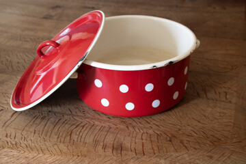 red  enamel polka dot  large cooking  pot  with  lid  on a  wooden farmhouse table  