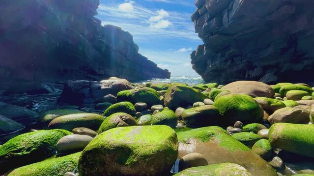 Sunlit rocky passage with vibrant moss-covered stones at Mullaghmore, County Sligo