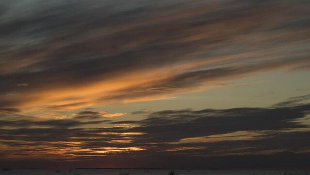 A bright cloudy orange sunset turning into red, clouds moving from left to right. No birds. You can trim the bottom edge of the video and stay in 4096*2160 standard. Time lapse.