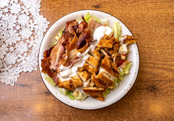 Polish Caesar salad with chicken, bacon and vegetables, high-calorie meat salad with fresh vegetables