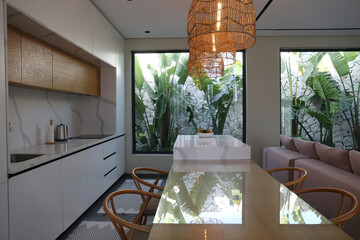 Stylish kitchen interior with big beautiful windows with a view on palms. Copy space, background.