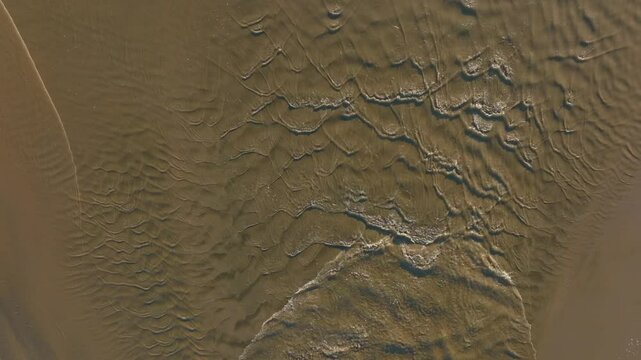 Abstract Texture of water ripples flowing into the ocean. Bethells Beach, Auckland, New Zealand.