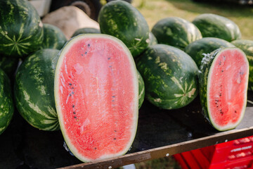 limbazi, Latvia, June 29, 2024 - Close-up of whole and halved watermelons on display at an outdoor market, showcasing the vibrant red flesh and seeds.