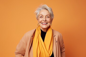 Cheerful senior woman in stylish clothes posing over orange background.