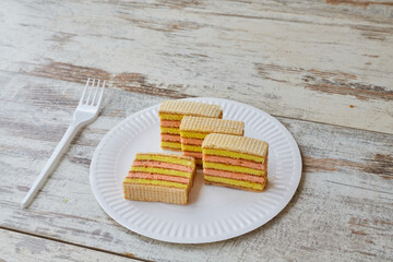 Yellow pink sponge cake with waffles and jam on a white plate, home baking, fruit sponge cake, closeup