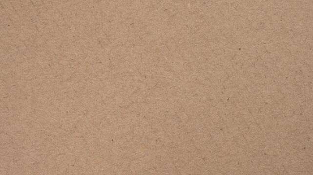 Cardboard sheet texture of recycled kraft brown paper box surface close up. Rotation