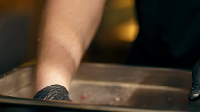 close-up in a restaurant in a rib bar in the central hall a chef in black gloves in an iron bowl mixes pieces of meat with marinade careful marinating