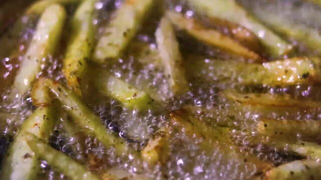 close up of potato fries deep frying in a pan