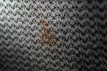 Fabric with small brown stain on patterned grey background