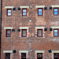 Pattern of brickwork, apartment windows and structural supports contained within a Victorian dockside warehouse restored and refurbished for urban living UK