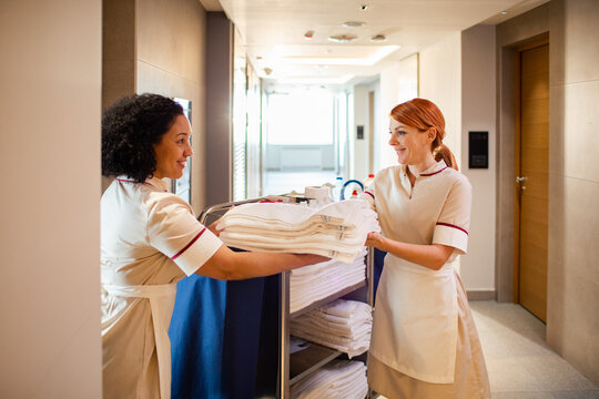 Hotel maids organizing towels on a cart in hallway