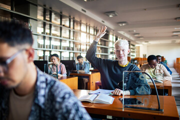 Student raising hand in university library classroom