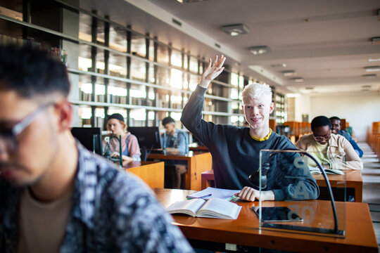 Student raising hand in university library classroom