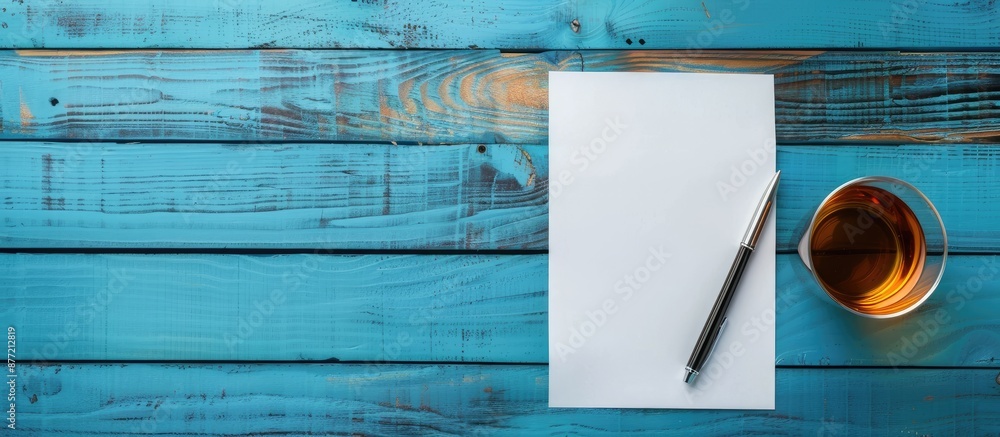 Aufkleber business desk concept with a pen on a blue wooden background an empty sheet of paper a glass of drin