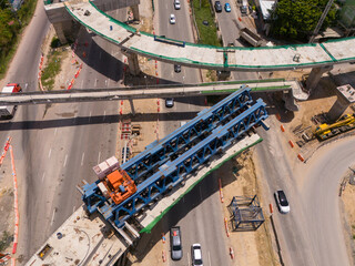 From above, witness the vibrant hustle of a modern tropical Asian traffic junction, where roads intersect amidst a dynamic flow of vehicles, creating a kinetic mosaic of urban movement.