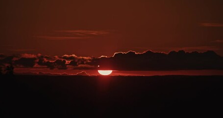 Sunset Sky Over Hills with Clouds and Light Timelapse: The setting sun colors the clouds in red and golden tones, slowly drifting over the hills, creating a magnificent view. 