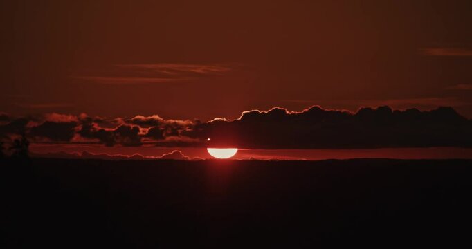 Sunset Sky Over Hills with Clouds and Light Timelapse: The setting sun colors the clouds in red and golden tones, slowly drifting over the hills, creating a magnificent view. 