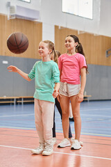 Naklejka premium girls stand confidently atop a basketball court, listening attentively to their male teachers instructions.