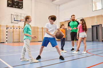 A diverse group of young people energetically playing a game of basketball, dribbling, passing, and shooting on a sunny court.