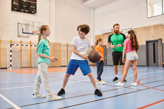 A diverse group of young people energetically playing a game of basketball, dribbling, passing, and shooting on a sunny court.