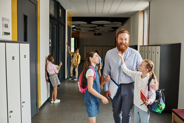Obraz premium A man with a comforting presence walks down a hallway with children, guiding them with care and kindness towards their destination.