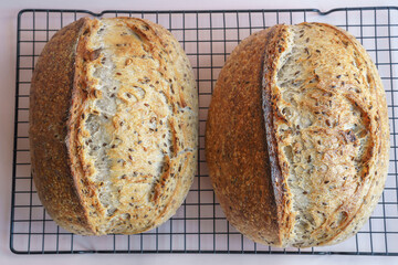 Handmade artisan bread with seeds on a cooking grid on a beige background.