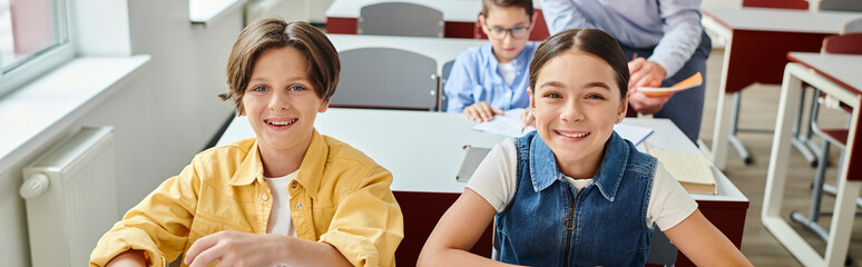 happy group of students at a table in a bright, bustling classroom.