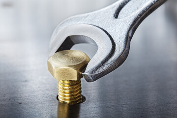 Wrench tightens bolt in steel billet. Spanner, bolt, screw and nuts.
