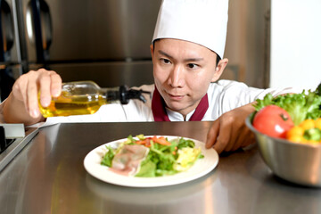 オリーブオイルをサラダにかける男性料理人