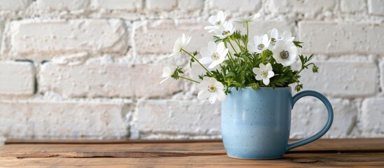 White wild anemone flowers in a blue mug against a white brick wall on a wooden table evoke a rural spring vibe with a copy space image for creative text placement