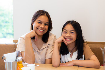 couple family came together in a cafe. Mom,  little daughter eat cakes and ice cream. They are happy together. Happy family lunch concept.