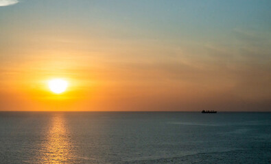 Obraz premium atardecer junto al mar y un barco pasando al fondo 