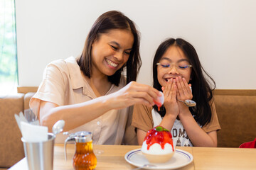 couple family came together in a cafe. Mom,  little daughter eat cakes and ice cream. They are happy together. Happy family lunch concept.