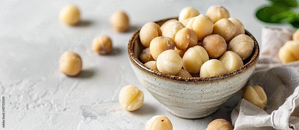 Poster peeled macadamia nuts displayed in a bowl on a bright table with copy space image available