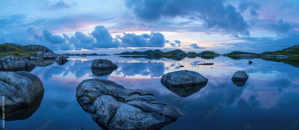 Poster Tranquil nature scene with rocks in the foreground mirrored in a lake under a twilight sky providing a serene ambience for a copy space image