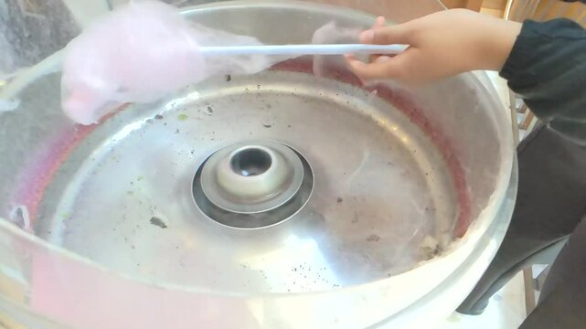 Cinematic shot of young woman hands spin cotton candy on machine. The concept of street food with a delightful treat for all ages, fun, and festive