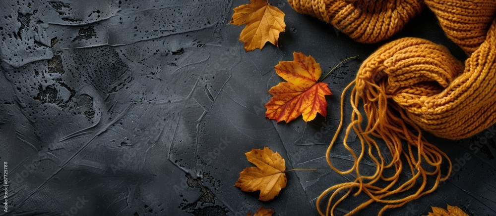 Poster autumn leaves on a dark backdrop with yellow knitting ideal for a copy space image