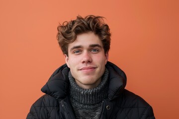 Obraz premium Portrait of a content caucasian man in his 20s sporting a quilted insulated jacket in front of solid color backdrop