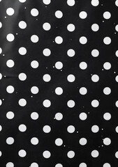 Black and white polka dot pattern on a black background in a flat lay, top view, high resolution copy space for text or logo.