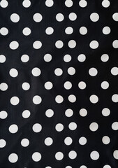 Black and white polka dot pattern on a black background in a flat lay, top view, high resolution copy space for text or logo.