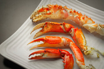 Four individual crab legs on a white plate