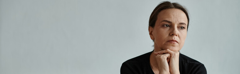 Middle-aged woman deep in thought, hand on chin.